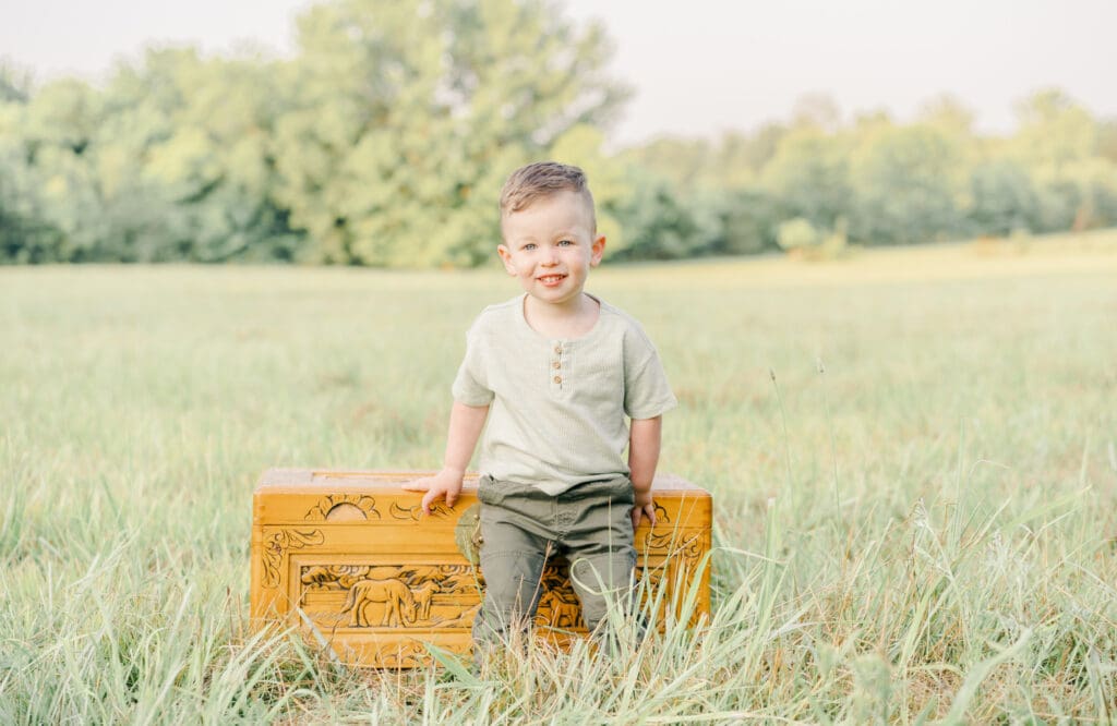 Toddler sitting on a wooden chest during an outdoor family photography session in Murfreesboro Tennessee