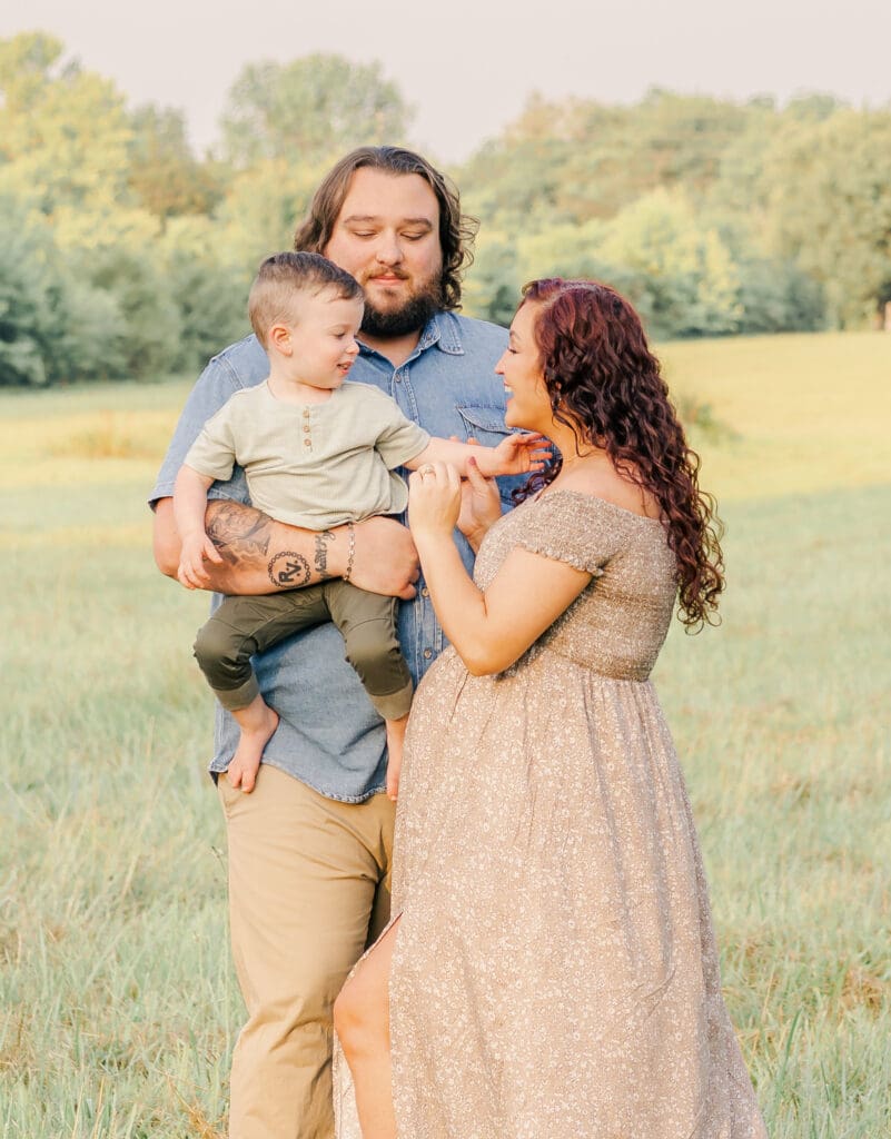 Family maternity portrait with father holding toddler while mother interacts with him in Murfreesboro Tennessee